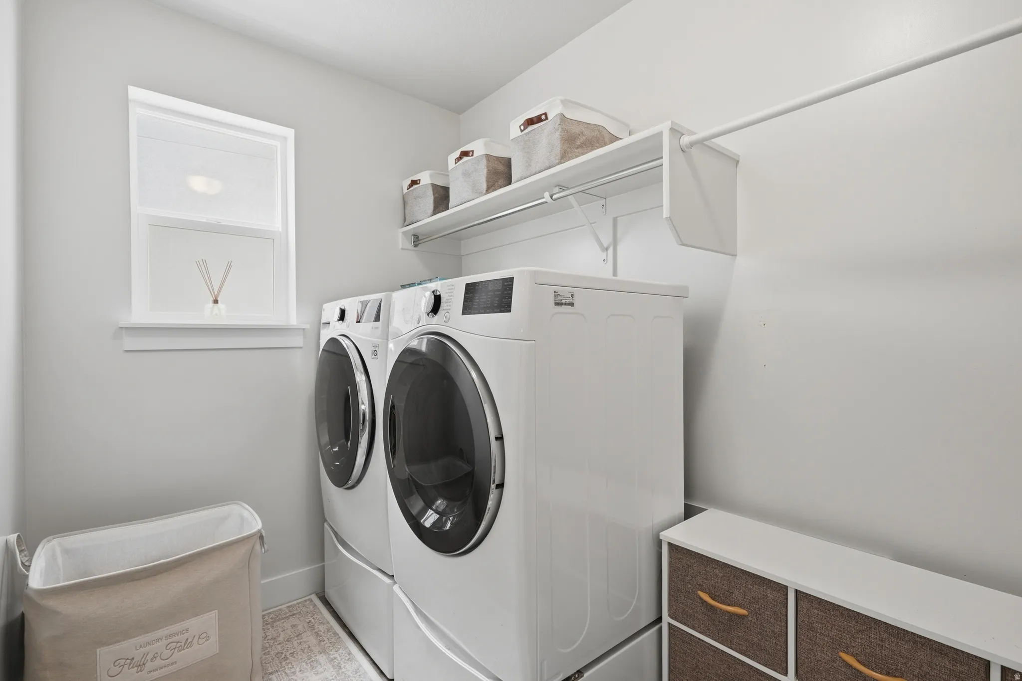Dedicated laundry area featuring a window, built-in shelving, and a hanging rod