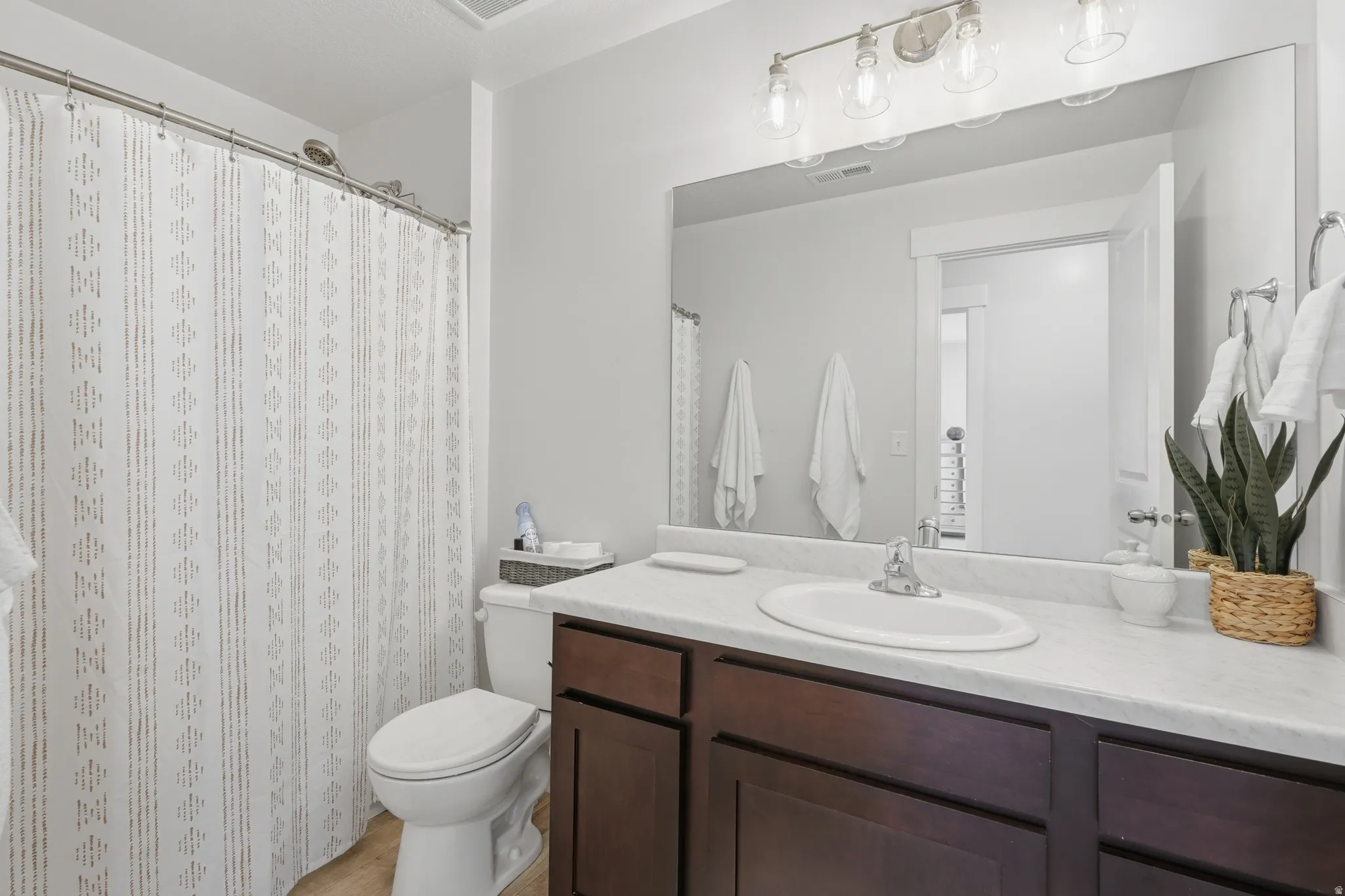 Full bathroom featuring a dark wood-finish vanity with a white countertop and integrated sink, chrome faucet, and a large mirror