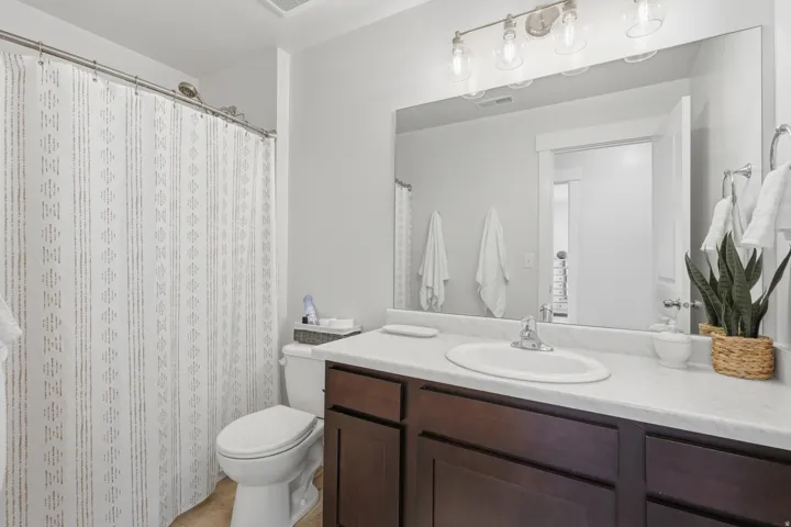 Full bathroom featuring a dark wood-finish vanity with a white countertop and integrated sink, chrome faucet, and a large mirror
