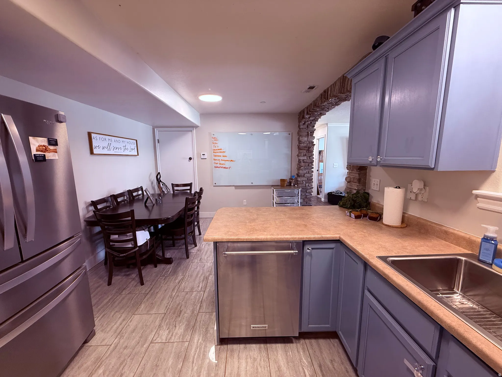 Kitchen featuring blue cabinetry, light-toned countertops, and a stainless steel dishwasher