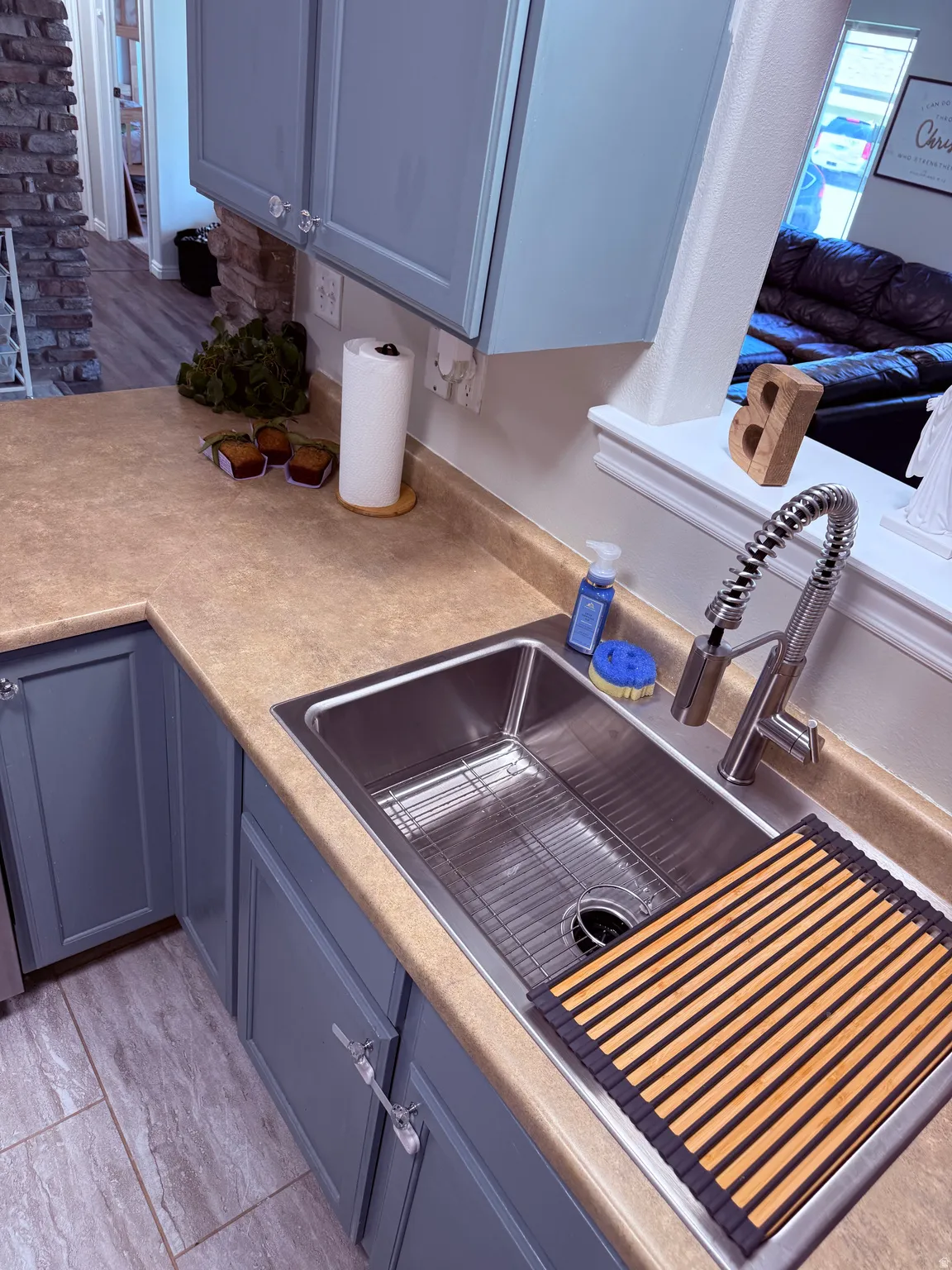 Kitchen sink area featuring a stainless steel undermount sink with a gooseneck pull-down faucet, composite countertops, and contemporary blue cabinetry