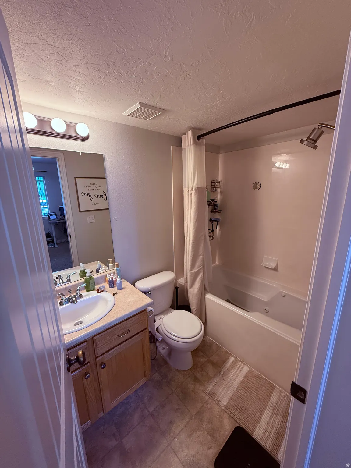 Bathroom featuring a single vanity with wood-finish cabinetry, a white porcelain sink, and a multi-bulb light fixture