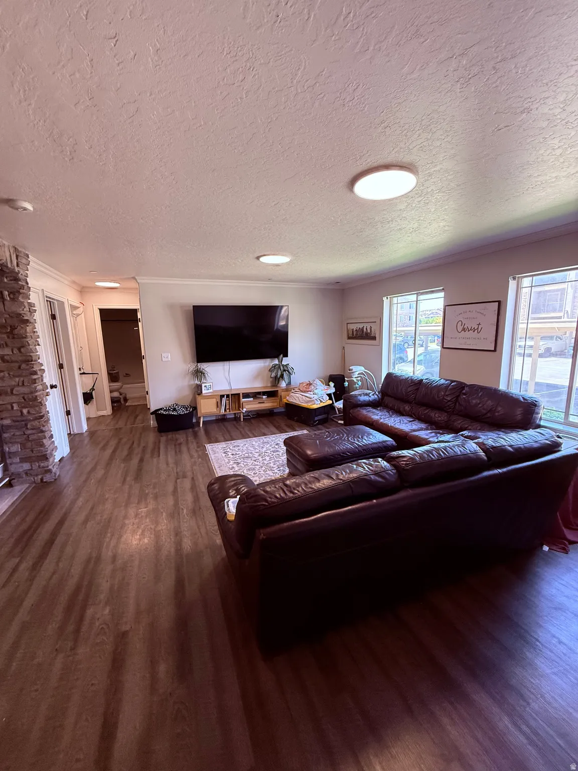Living area featuring wood-finish flooring, a stone-clad fireplace, and multiple windows