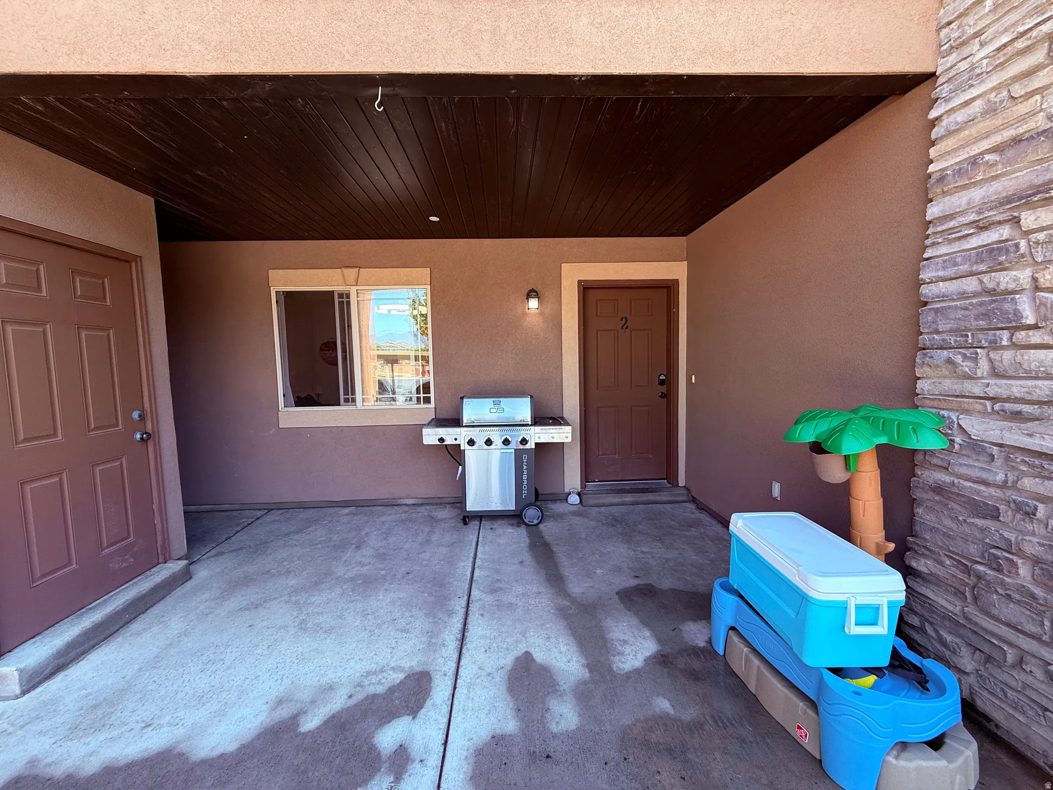 Covered patio featuring a concrete slab, stucco exterior, and a stone veneer column