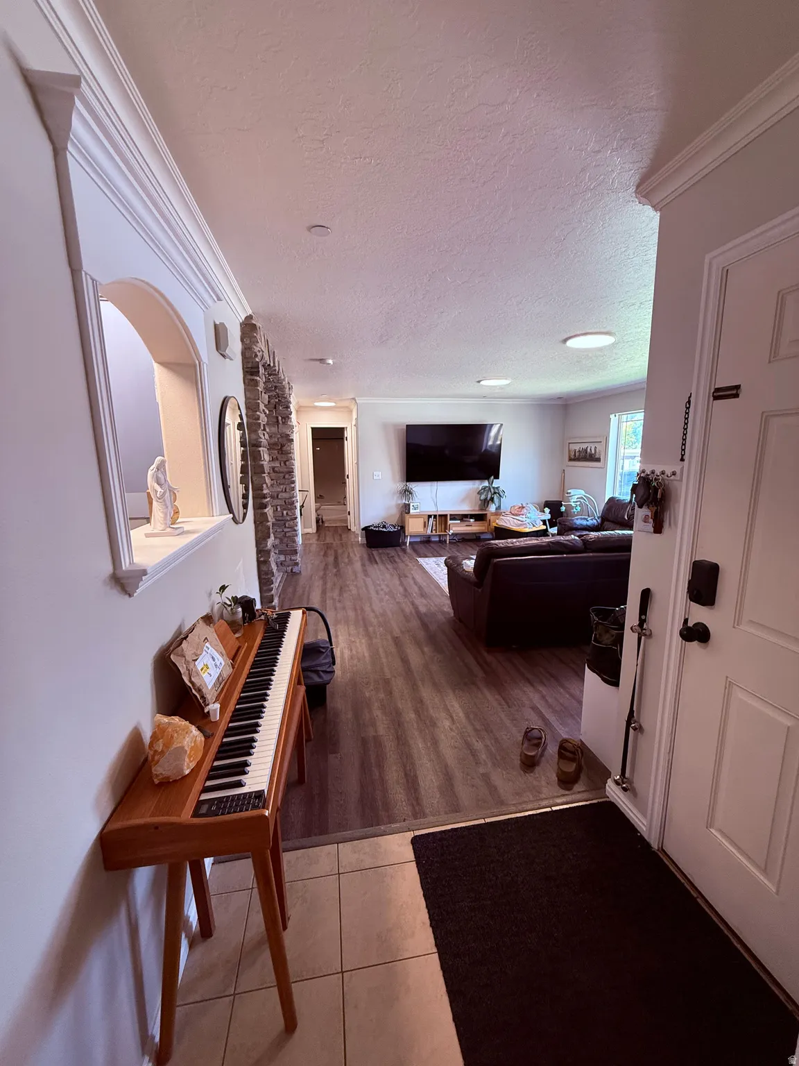 Entryway featuring tile flooring, crown molding, and an arched wall niche