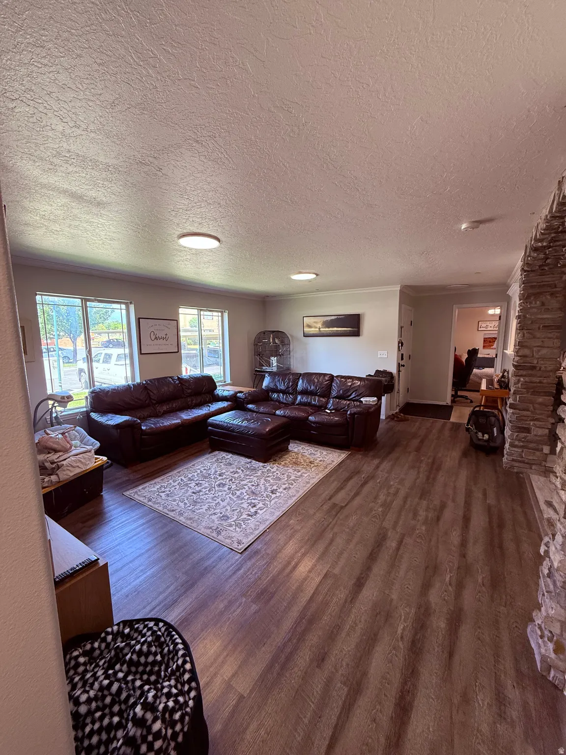 Spacious living area featuring wood-finish flooring, recessed lighting, and a stacked stone accent wall