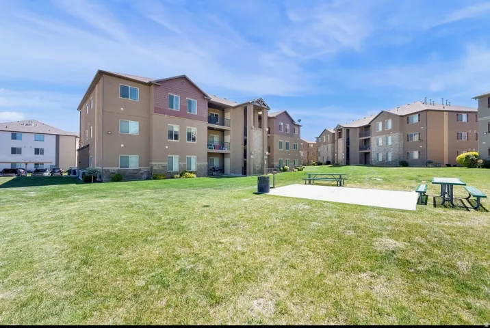 Expansive outdoor area featuring a manicured lawn, paved patio, and picnic tables