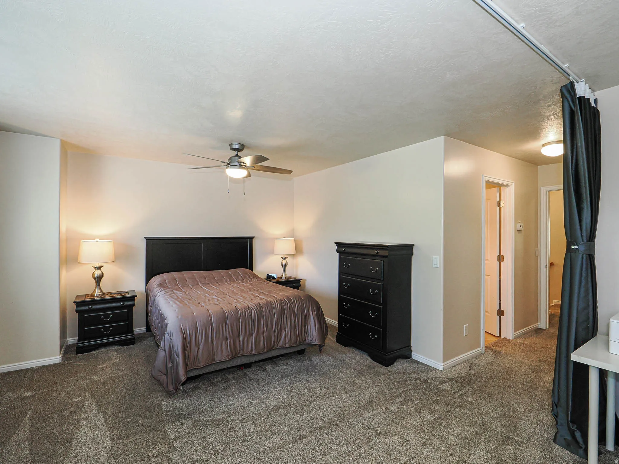 Carpeted bedroom with a ceiling fan, neutral wall tones, and white trim