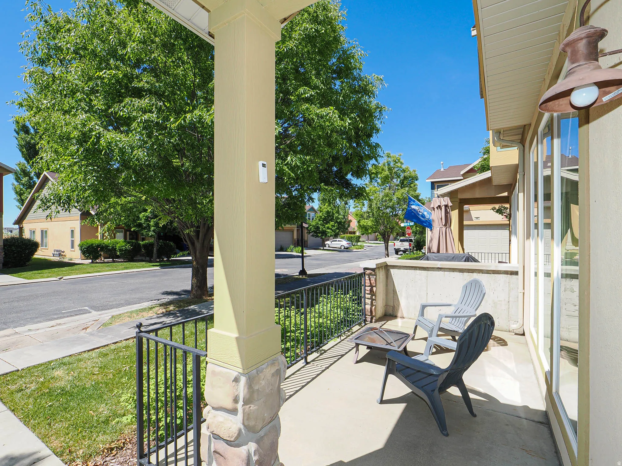 Covered porch featuring a concrete floor, stone-wrapped columns, and a black wrought-iron railing