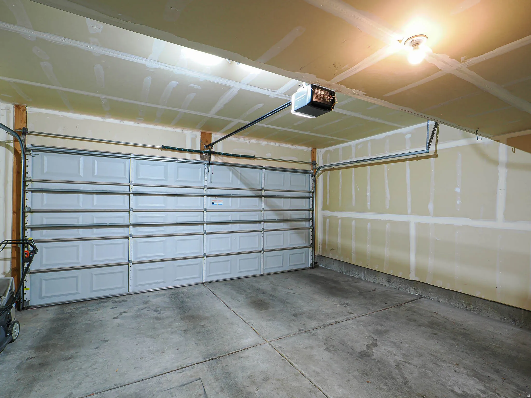Single-bay garage featuring a panel-style door, concrete flooring, and an exposed ceiling with track for an automatic opener