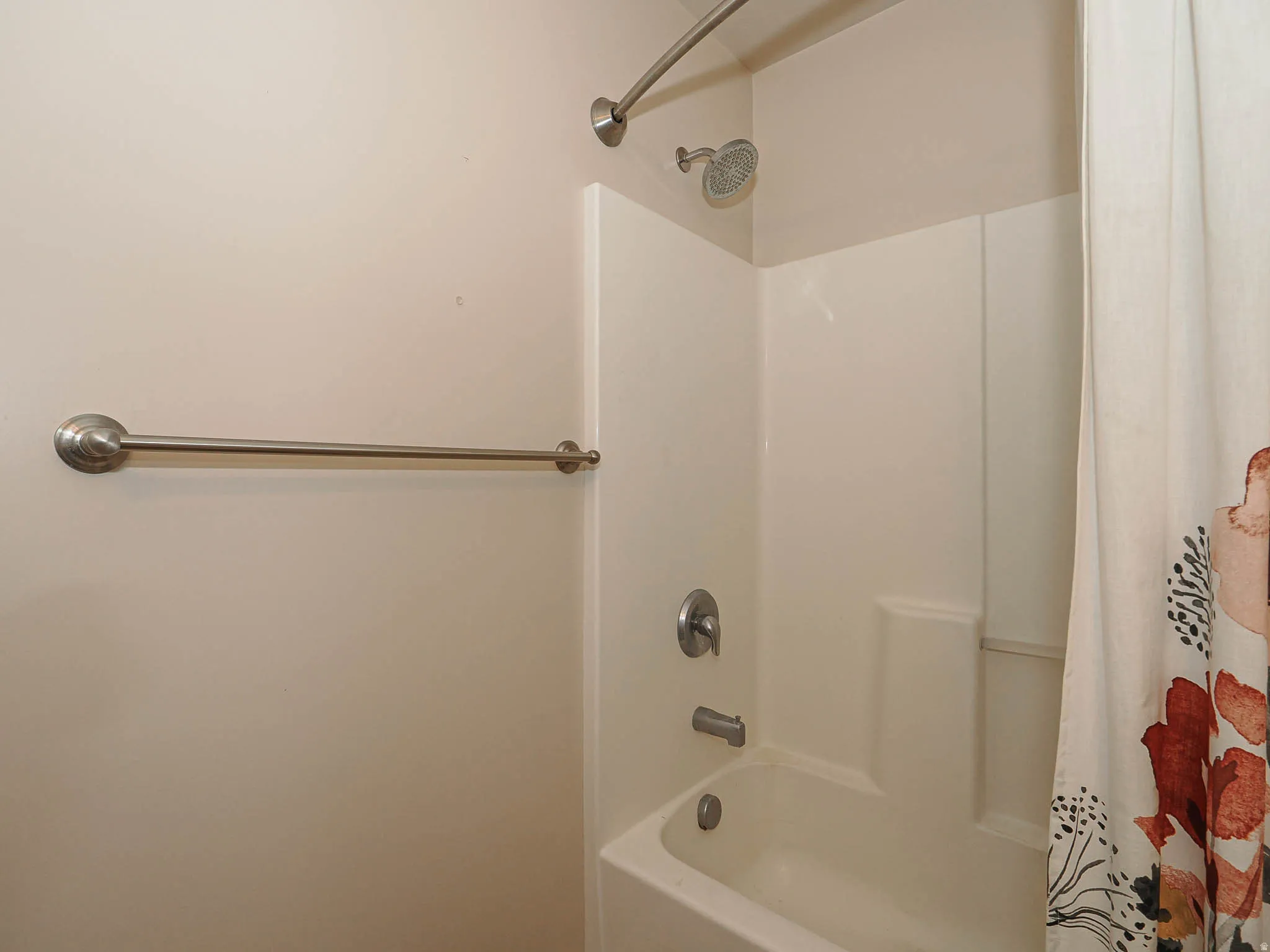 Bathtub and shower combination featuring a curved shower rod and brushed nickel fixtures