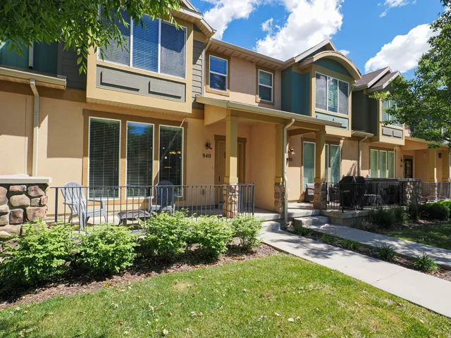 Multi-story townhome exterior featuring an inviting covered porch, stone accents, and varied architectural elements