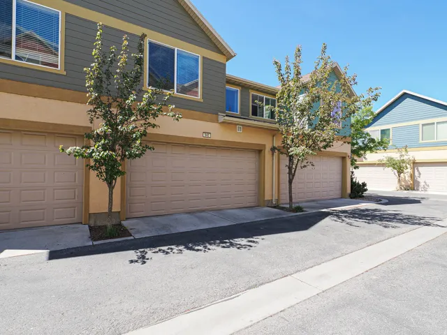 Exterior featuring neutral tone garage doors, stucco and horizontal siding facade, and mature trees