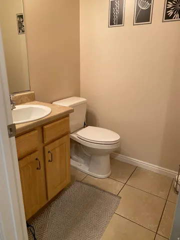 Powder room featuring a single-basin vanity with a wood-finish cabinet and a beige countertop