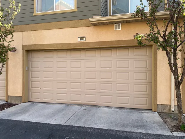 Integrated single-car garage featuring a panel-style door, concrete driveway, and stucco exterior