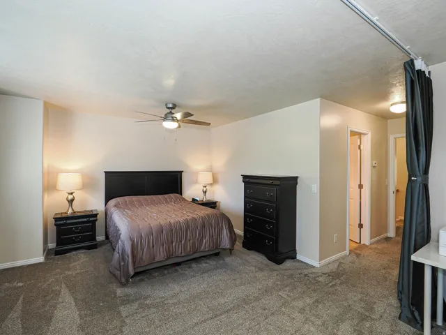 Carpeted bedroom with a ceiling fan, neutral wall tones, and white trim