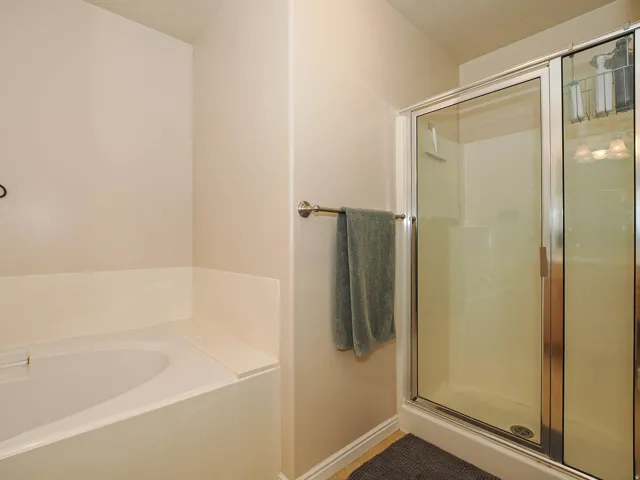 Built-in tub with a tiled surround and a glass-enclosed shower with chrome fixtures