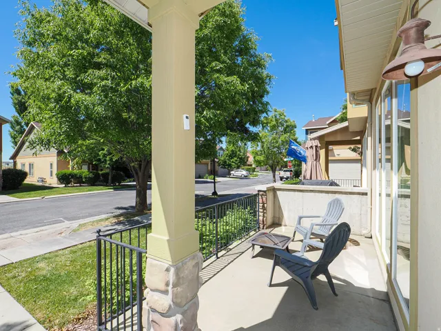 Covered porch featuring a concrete floor, stone-wrapped columns, and a black wrought-iron railing