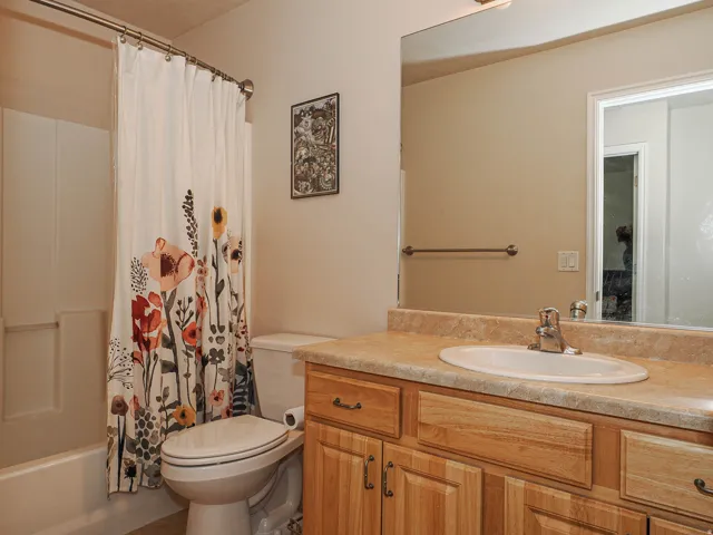 Bathroom featuring a light wood vanity with an integrated sink, a laminate countertop, and a large wall-mounted mirror
