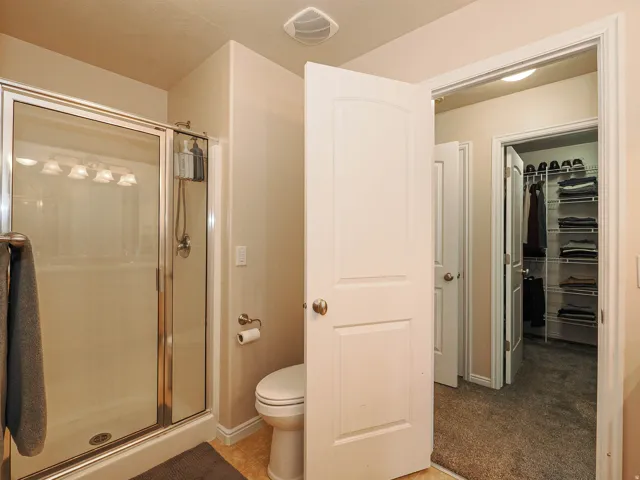 Shower enclosure with sliding glass doors, overhead light fixture, and a toilet