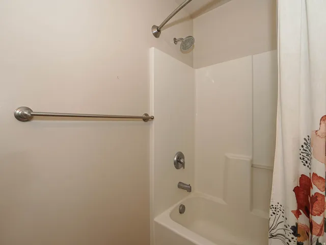 Bathtub and shower combination featuring a curved shower rod and brushed nickel fixtures
