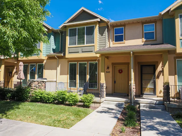 Multi-story townhome exterior featuring an inviting front porch with stone accents and a covered entryway
