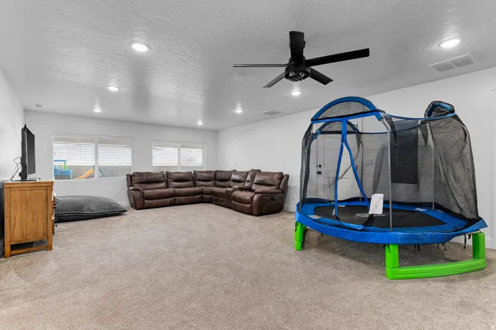 Spacious room featuring neutral carpet flooring, recessed lighting, and a ceiling fan