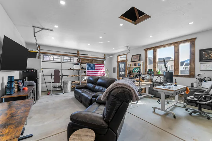 Spacious room featuring a concrete floor, overhead lighting, and abundant natural light from multiple windows