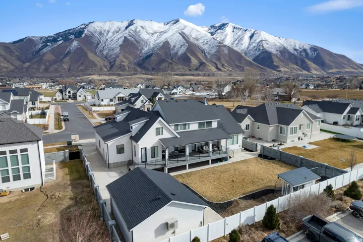 Contemporary white exterior featuring a covered deck, dark gray roofing, and a detached structure
