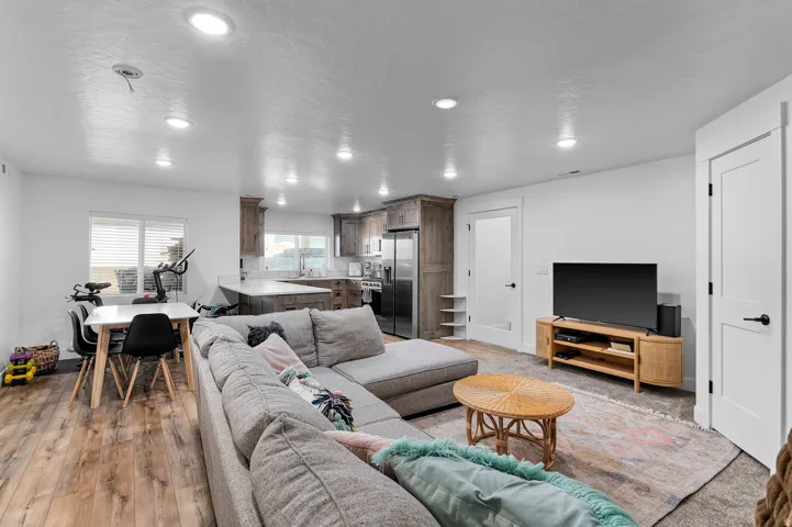 Open-concept living area featuring wood-finish flooring, recessed lighting, white walls, and a kitchen with wood cabinetry and light-colored countertops