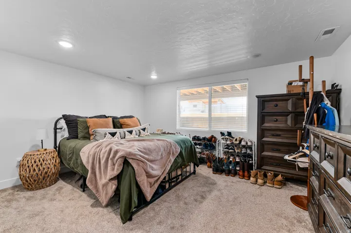 Spacious room featuring neutral carpeting, a large window with horizontal blinds, and recessed lighting