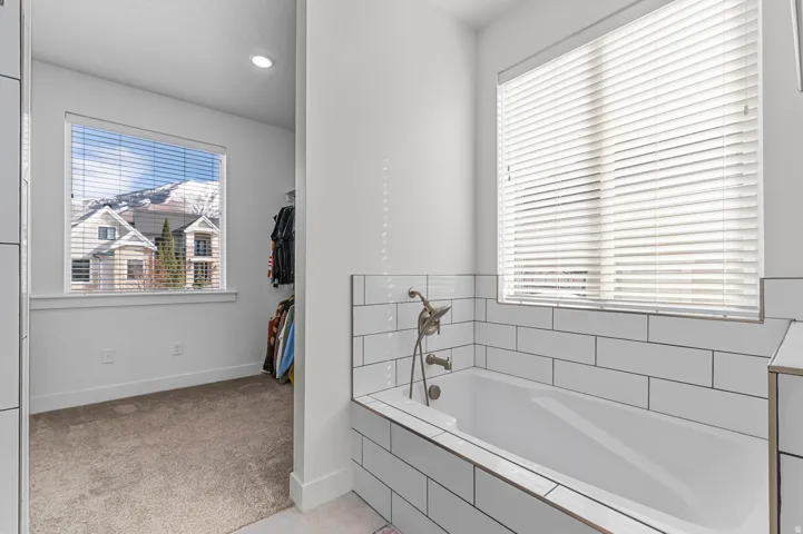 Soaking tub featuring white subway tile surround and brushed nickel fixtures