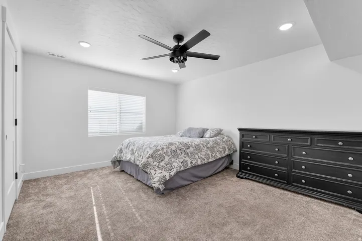 Carpeted room featuring a ceiling fan, recessed lighting, and a window with blinds