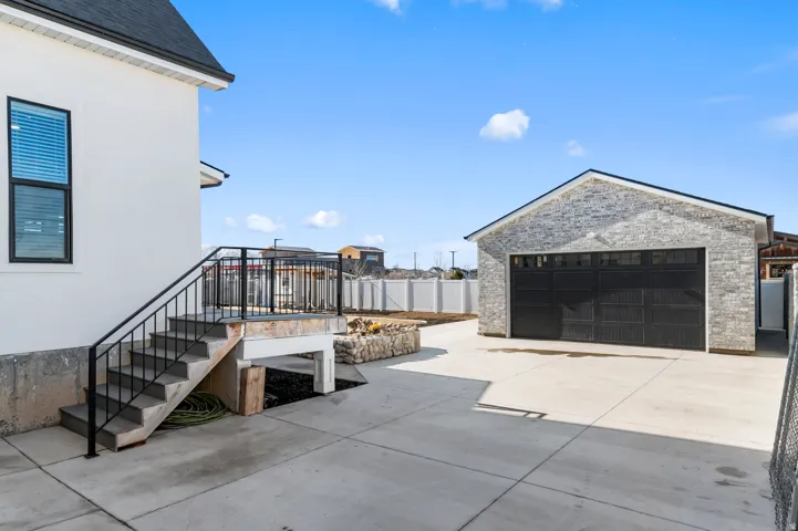 Detached garage with light-toned stone veneer and a black overhead door