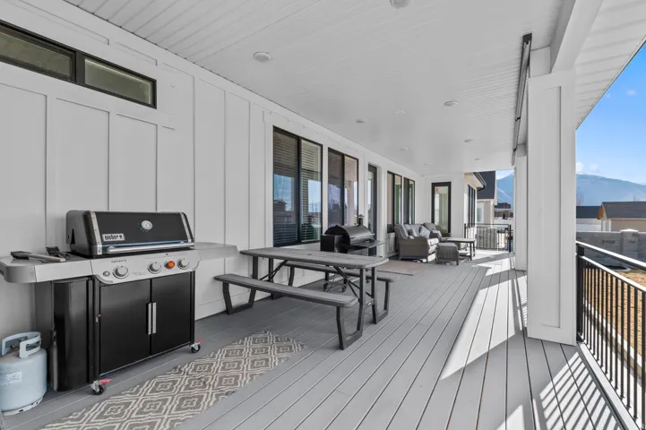 Expansive covered porch featuring composite decking and a white tongue-and-groove ceiling with recessed lighting