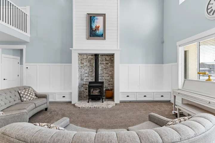 Living area featuring a floor-to-ceiling shiplap fireplace surround with a brick-lined hearth and wood-burning stove