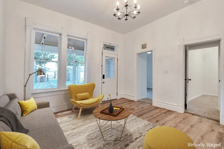 White walls, wood-finish flooring, two window openings, two door openings, and a chandelier lighting fixture