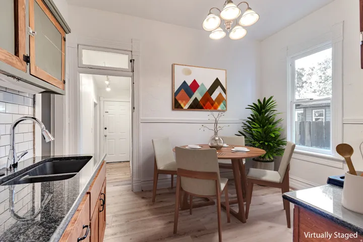 Kitchen featuring wood cabinetry, dark granite countertops, stainless steel sink with a gooseneck faucet, subway tile backsplash, and wood-finish flooring