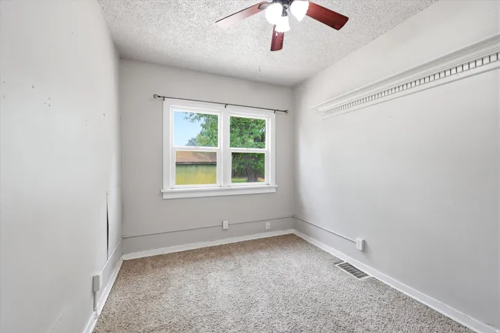 Carpeted room with a ceiling fan, crown molding, and a double-hung window