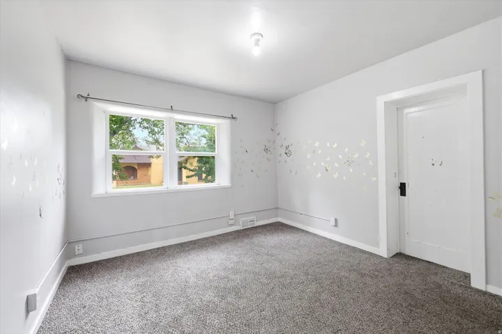 Bright room with neutral gray walls, a window offering natural light, and gray carpeting