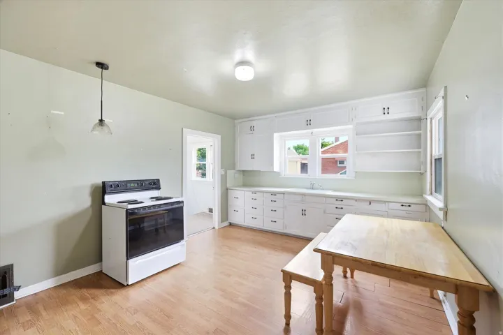 Kitchen featuring extensive white cabinetry, a single basin sink, and wood-finish flooring