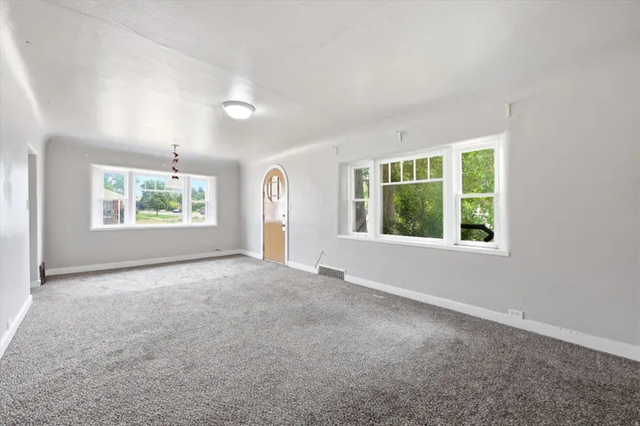 Spacious interior room featuring light gray walls and plush gray carpeting