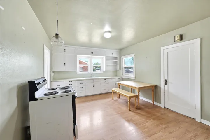 Kitchen featuring extensive white cabinetry, a built-in sink, and wood-finish flooring