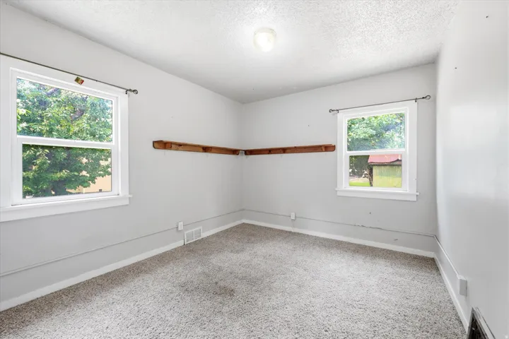Neutral gray wall paint with white trim, gray carpet, and two double-hung windows