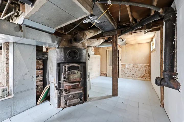 Basement utility area featuring exposed brick, an antique furnace, and visible ductwork