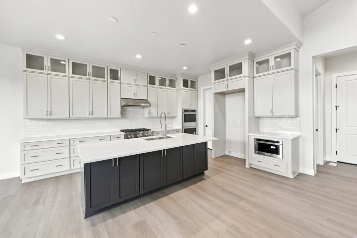 Kitchen featuring a contrasting island, recessed lighting, wood-finish flooring, a white subway tile backsplash, and stainless steel appliances