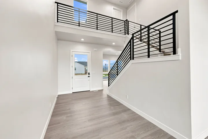 Two-story entry with wood-finish flooring, recessed lighting, and a modern horizontal bar railing system