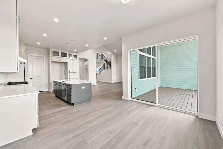 White cabinetry, light wood-finish flooring, and a kitchen island with sink