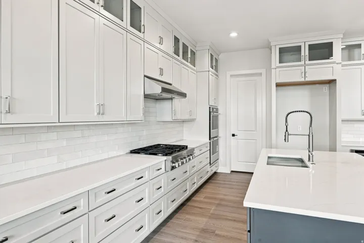 Gourmet kitchen featuring white shaker cabinetry, stainless steel appliances, a gas range, white subway tile backsplash, and light-toned countertops