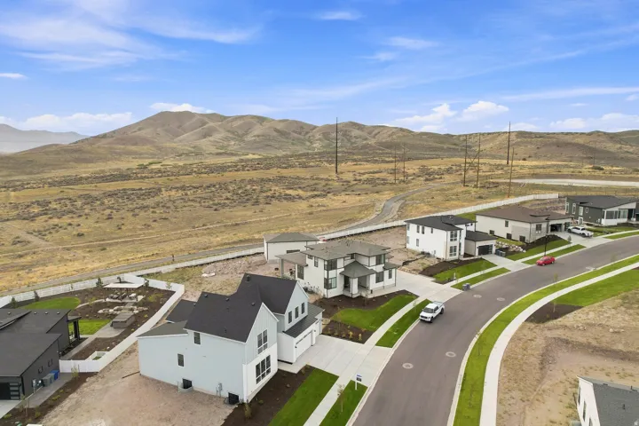 Residential development featuring contemporary architecture, paved streets with sidewalks, and landscaped common areas, all set against a prominent mountainous backdrop
